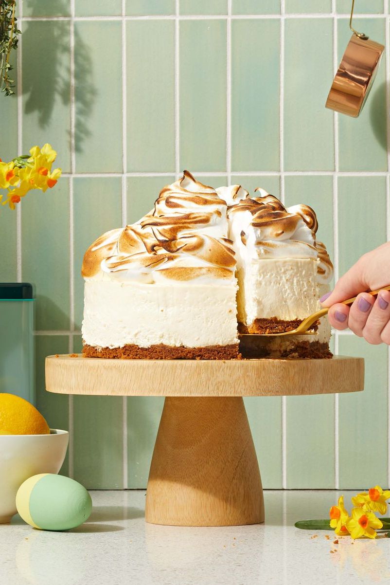 lemon meringue cheesecake on a wooden cake stand