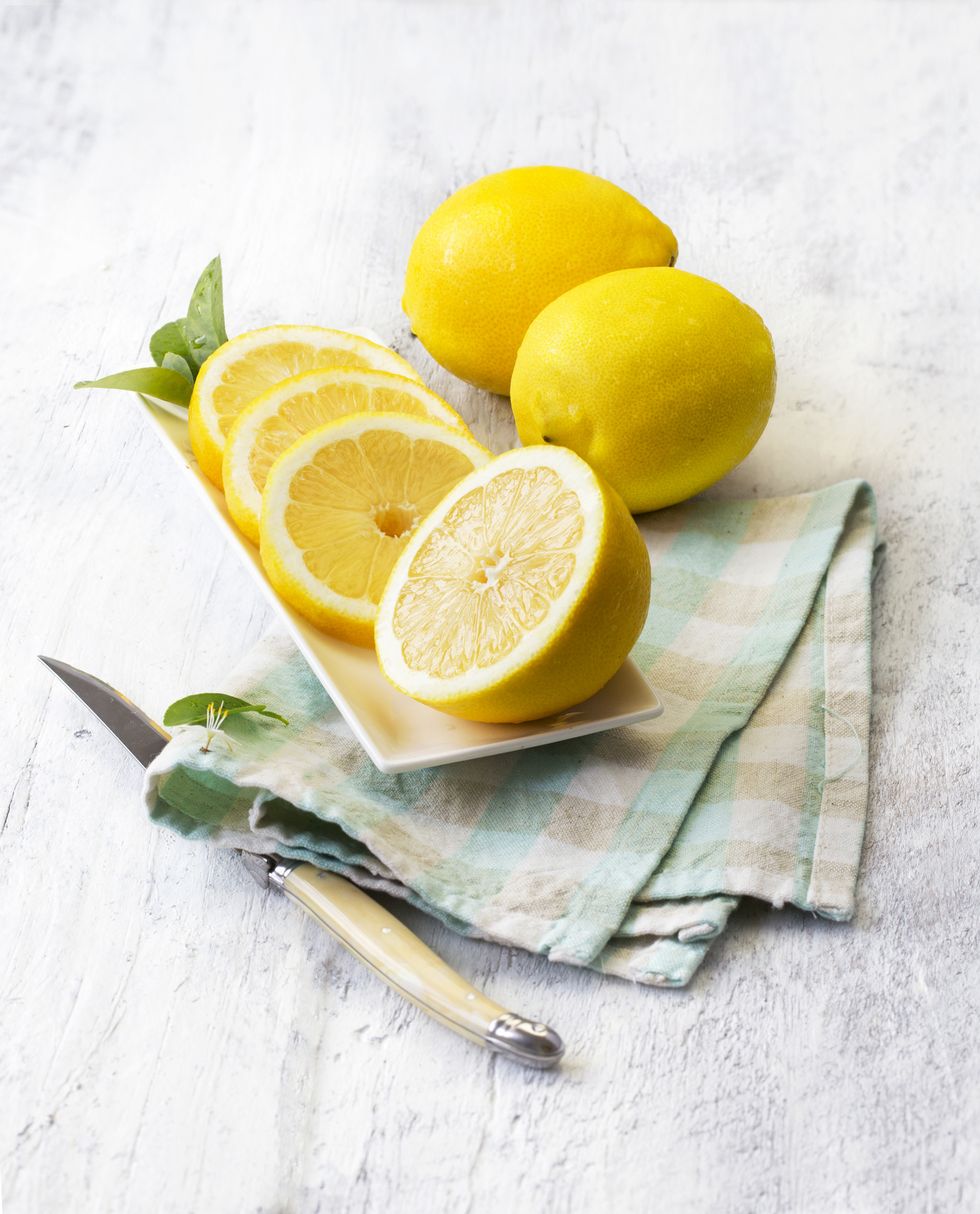 limones cortadas sobre una tabla de madera, un cuchillo y un trapo de cocina