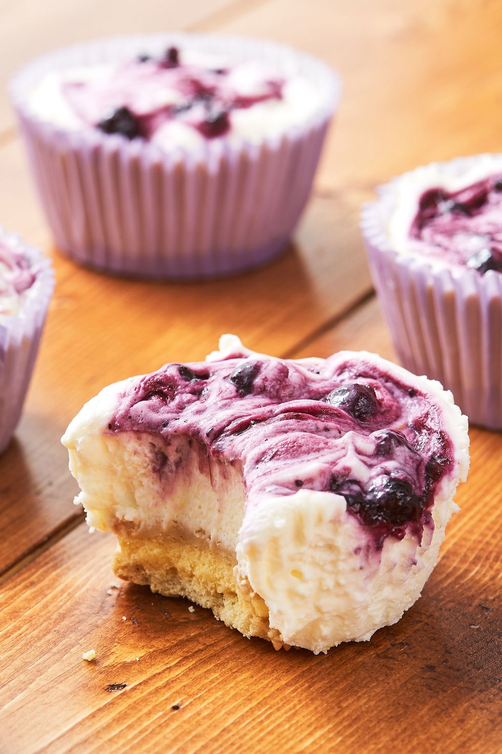 lemon blueberry mini cheesecakes, one with a bite out of it