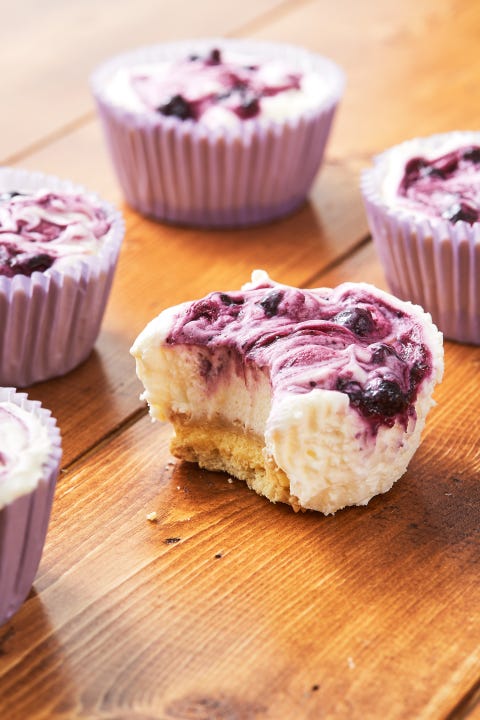 lemon blueberry mini cheesecakes, one with a bite out of it lemon blueberry mini cheesecakes, one with a bite out of it