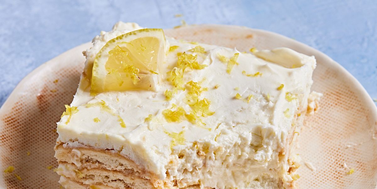square slice of lemon icebox cake with a bite out on an off white plate on a blue background