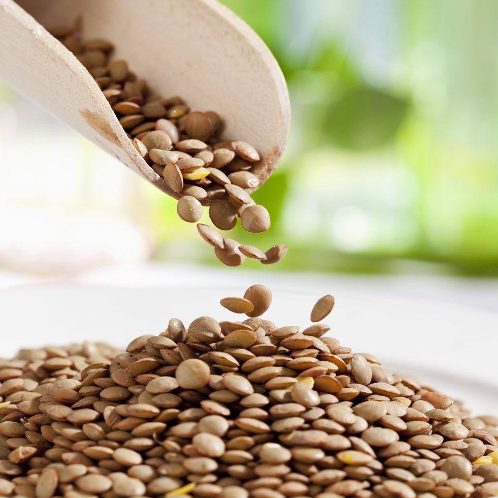 lentils pouring from wooden scoop, close up