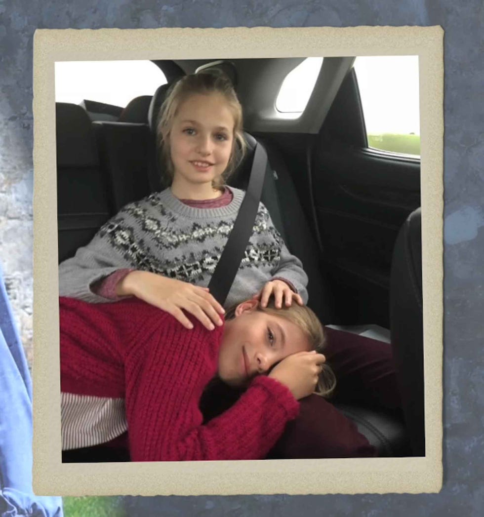 two individuals resting in a car seat one laying down while the other sits beside