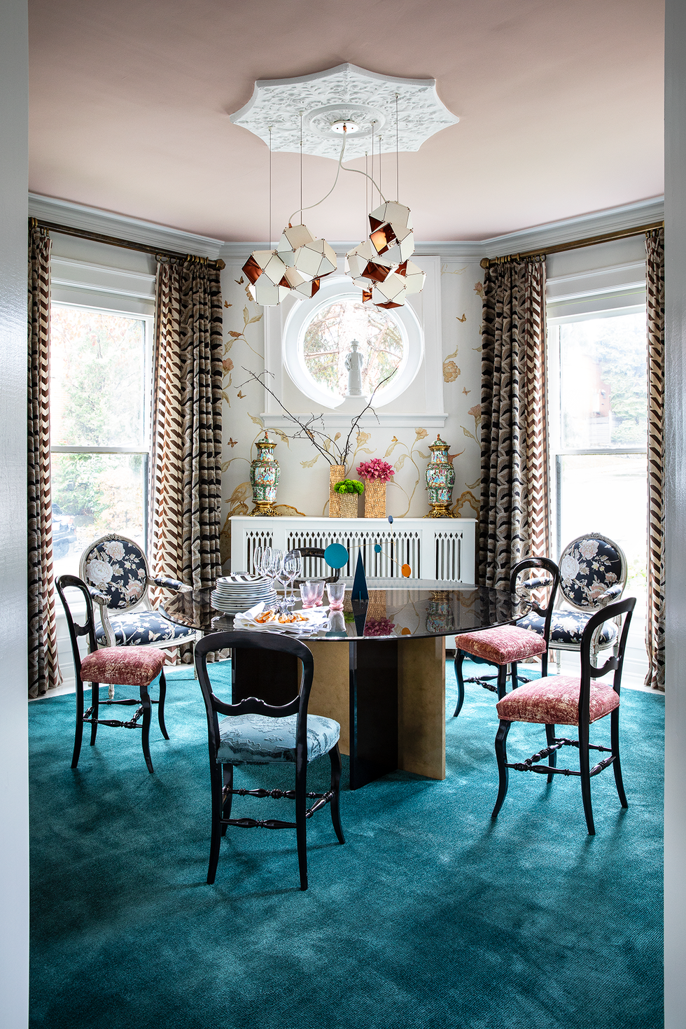 eclectic dining room with geometric chandelier and teal rug