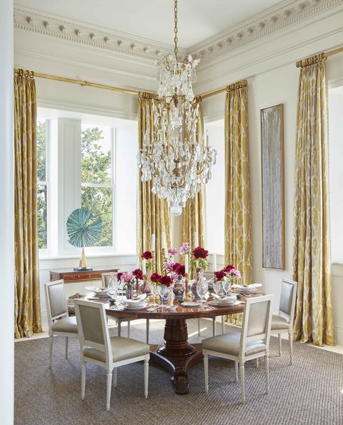 custom chairs are covered in shagreen leather in a corner dining area with a crystal chandelier and flowers on a grandly set table