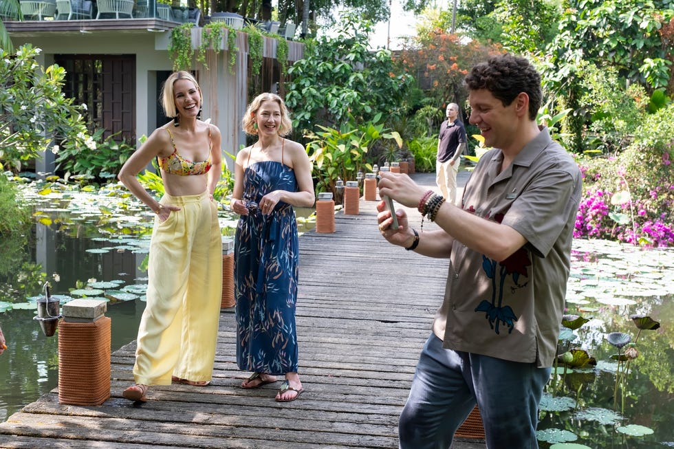 group of people enjoying a day in a garden with a wooden walkway and lily pond