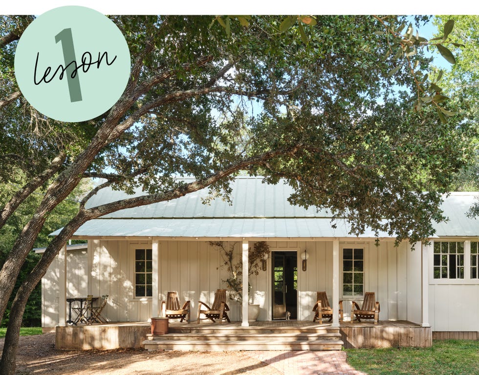 house with covered porch and wooden furniture surrounded by greenery