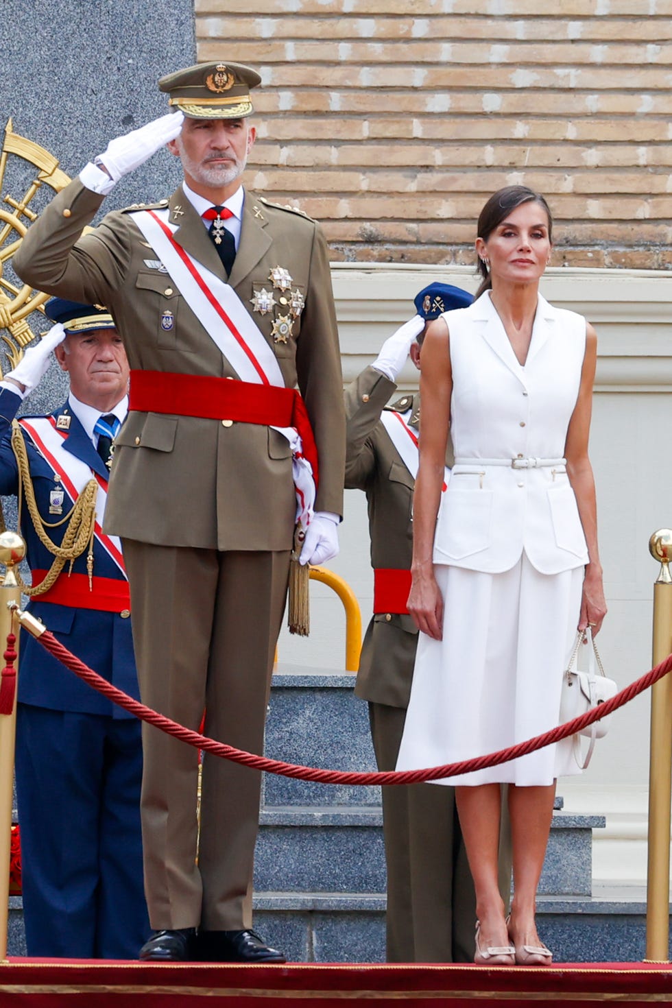 la reina letizia y el rey felipe en el acto de entrega de reales despachos de empleo de la academia militar 2023, letizia con vestido blanco de felipe varela