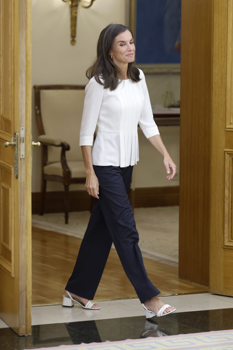 la reina con una blusa blanca y un pantalon azul marino