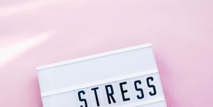 la palabra 'estrés' en inglés sobre un letrero luminoso con un fondo rosa