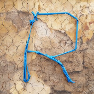 een blauwe r gemaakt van touw op een cementen ondergrond