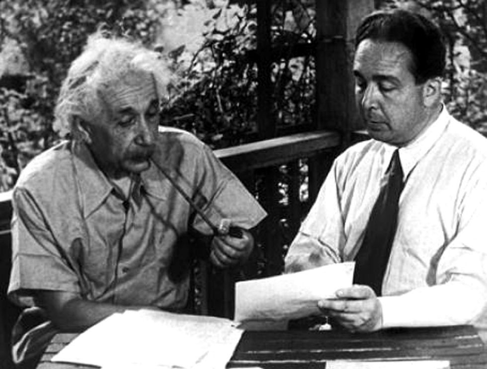 albert einstein and leo szilard sitting at a table, looking over a letter