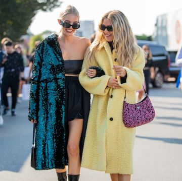 milan, italy   september 24 leonie hanne seen wearing green glitter coat, black top, skirt, bag, boots and emili sindlev wearing yellow coat, pink prada bag outside prada during the milan fashion week   spring  summer 2022 on september 24, 2021 in milan, italy photo by christian vieriggetty images