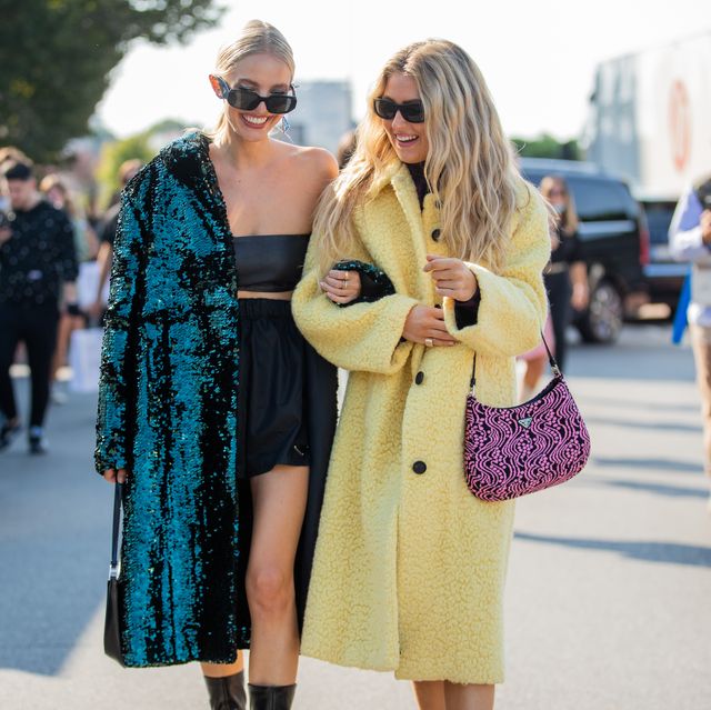 milan, italy   september 24 leonie hanne seen wearing green glitter coat, black top, skirt, bag, boots and emili sindlev wearing yellow coat, pink prada bag outside prada during the milan fashion week   spring  summer 2022 on september 24, 2021 in milan, italy photo by christian vieriggetty images