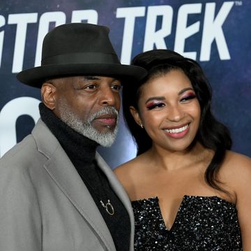levar burton and mica burton, levar wears a black tribly hat, mica burton is smiling and wearing a strapless dress