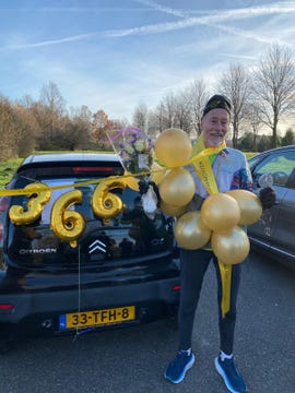 celebratory scene with balloons and flowers around a car