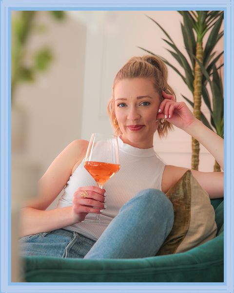 lexi stephens sitting on chair with a glass of orange wine