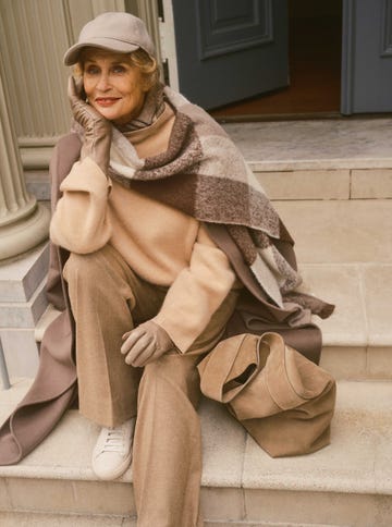 A person seated on stairs wearing layered clothing and accessories