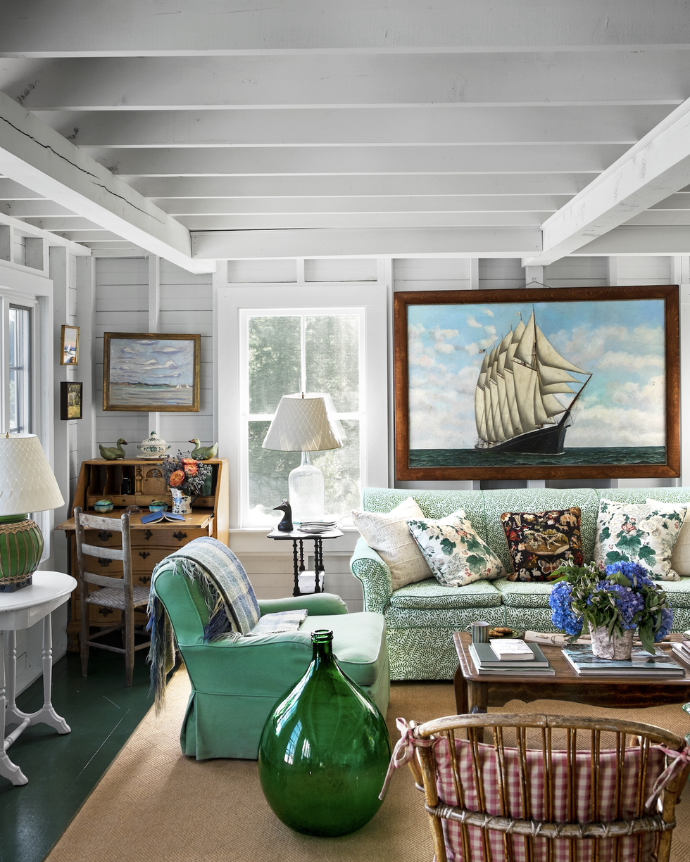 collected maine living room with a green sofa and a giant vintage ship painting on the wall