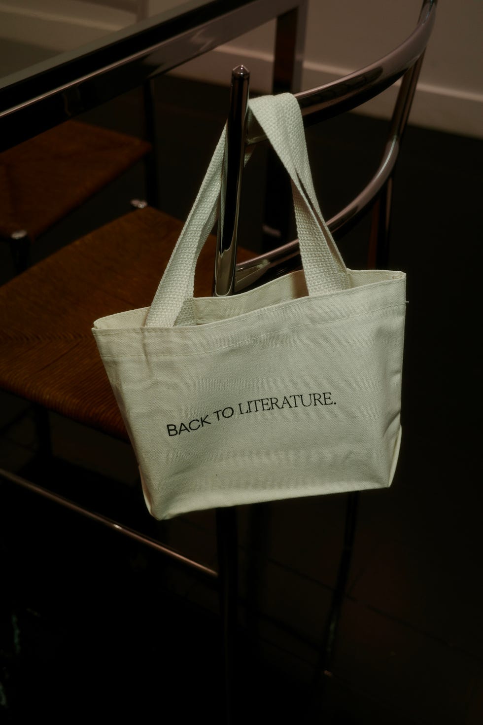 a mini tote bag reading 'back to literature' slung on the back of a chair