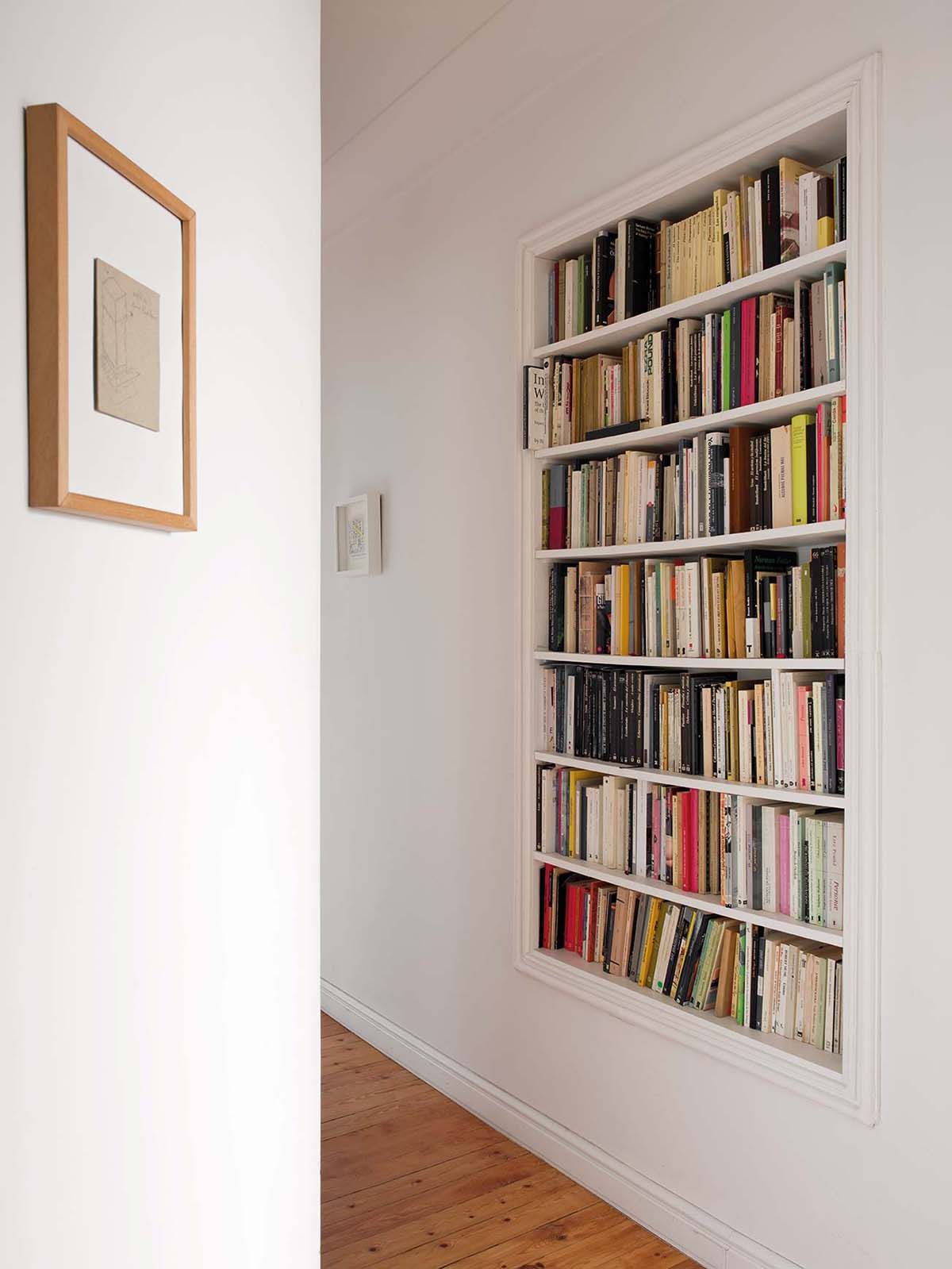 Una librería blanca con libros y una imagen de un libro en la pared.