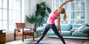  Woman stretching in her front room, to demonstrate the story "This PT has an amazing method to stay motivated while working out at home"