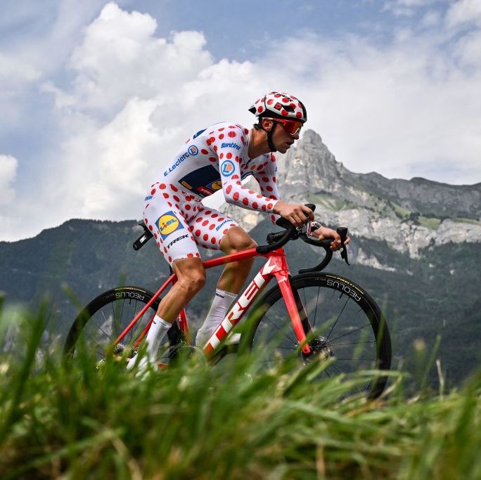 a cyclist wearing a polka dot jersey rides through the mountains