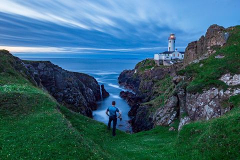 Wolkenflarden en een blauwe zee omlijsten het 202 jaar oude Fanad Head Lighthouse op Donegal in Ierland een vuurtoren op de toeristische route Wild Atlantic Way In de buurt liggen de zeeklippen Slieve League Cliffs die tot de hoogste van Europa behoren
