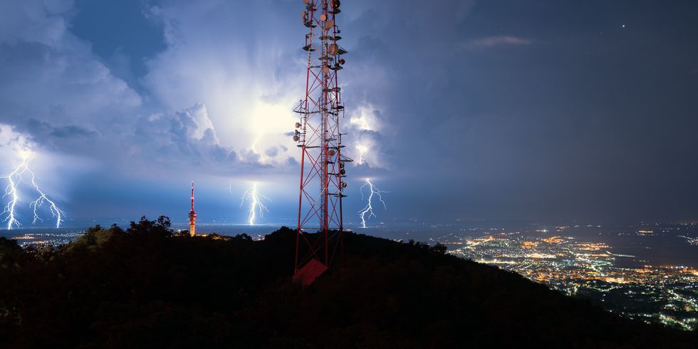 lightnings above city behind transmission tower