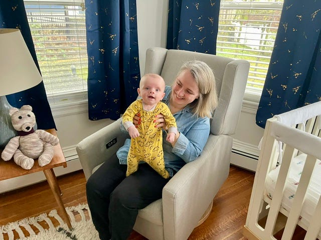 a mom sits with her baby on the glider in a nursery