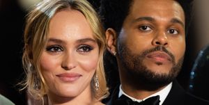 lily rose depp, wearing a green dress, and the weeknd, wearing a black tuxedo, smiling for the camera