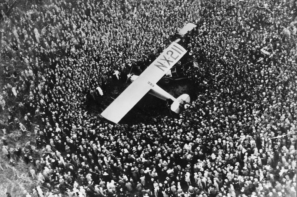 a crowd of people surrounds a monoplane