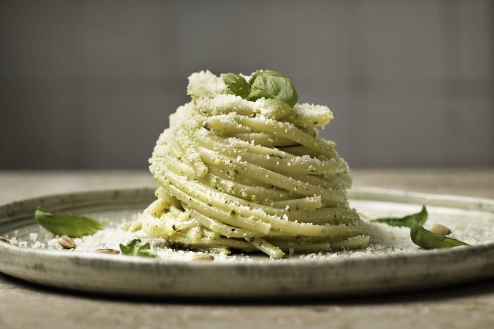 linguine pesto pasta on plate with pine nuts and basil