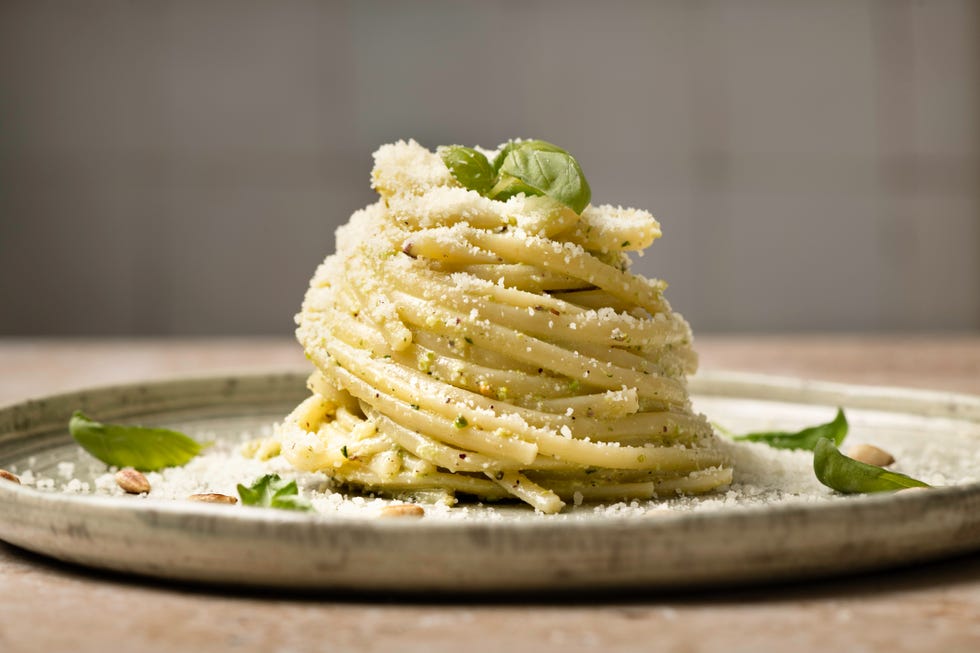 linguine pesto pasta on plate with pine nuts and basil