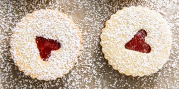 linzer cookies with a raspberry jam filling and a heart shaped cut out, topped with powdered sugar