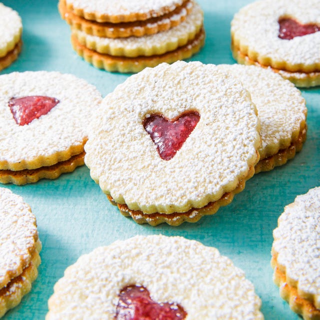 linzer cookies with a raspberry jam filling and a heart shaped cut out, topped with powdered sugar