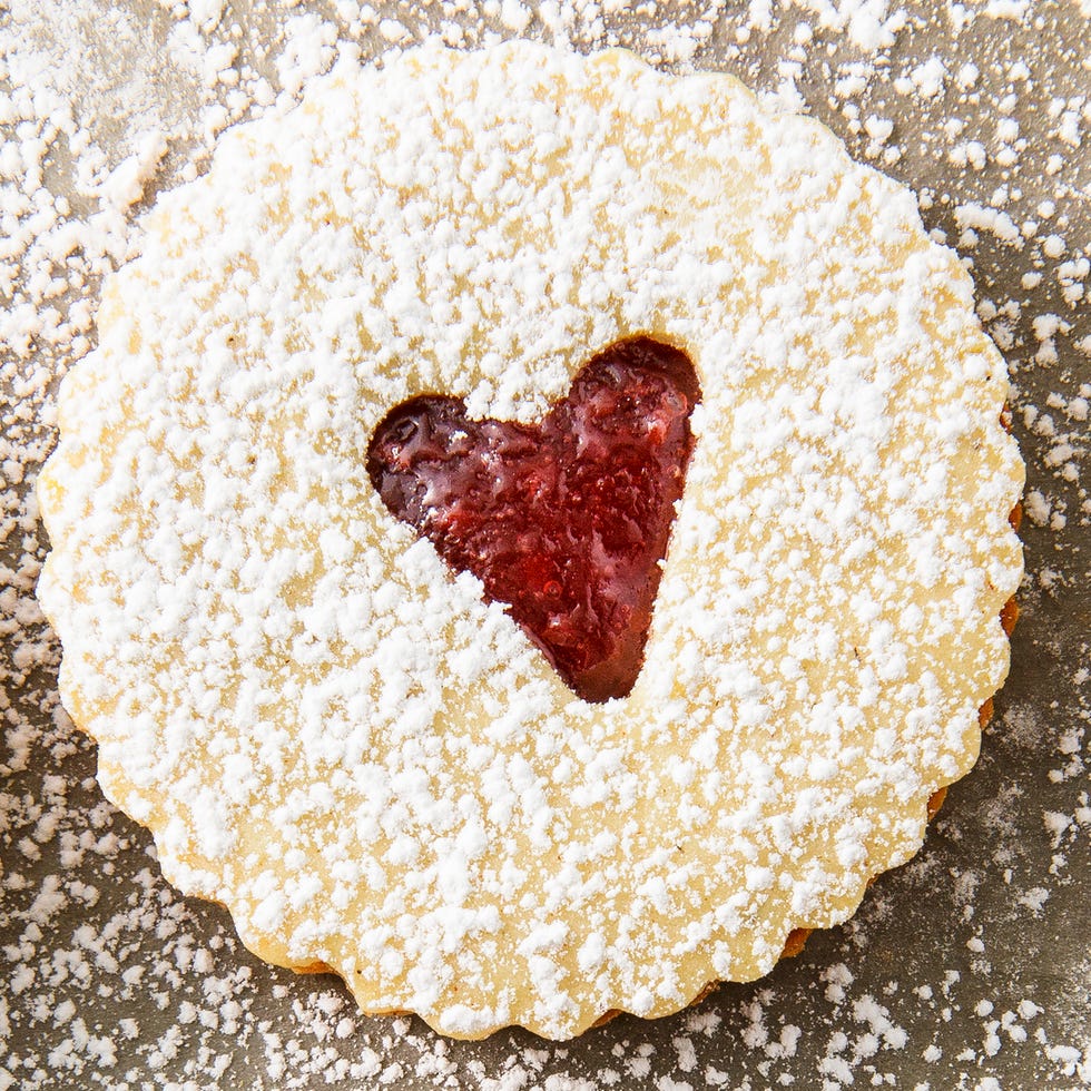 linzer cookies with a raspberry jam filling and a heart shaped cut out, topped with powdered sugar