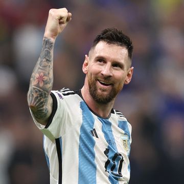 lionel messi wears an argentina soccer uniform and lifts one fist into the air while smiling