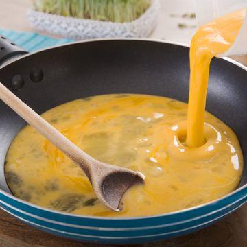 liquid egg for scrambled eggs is being poured into frying pan