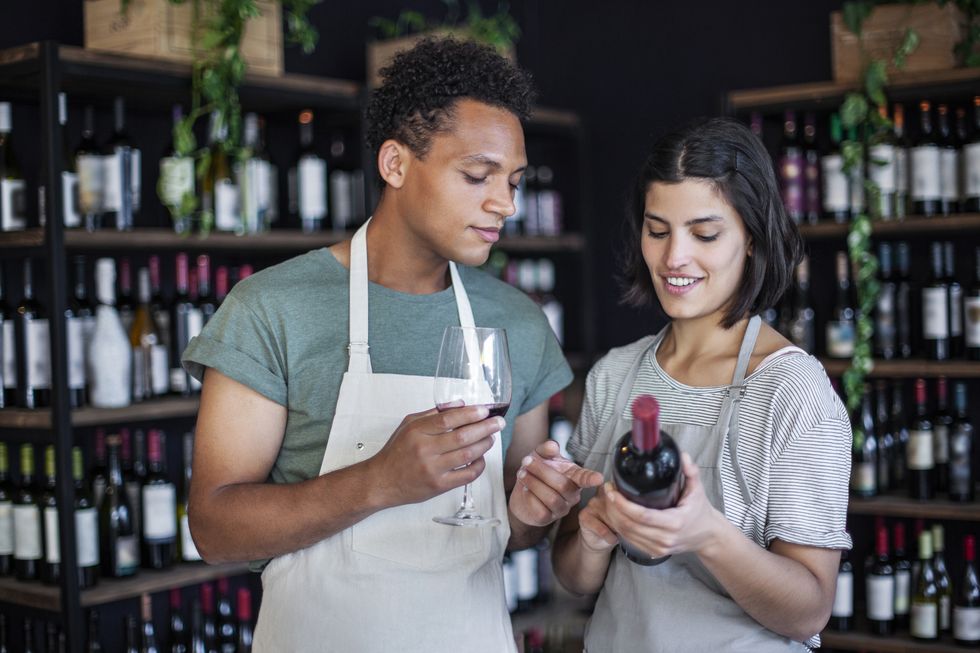 liquor store coworkers holding bottle and glass of wine