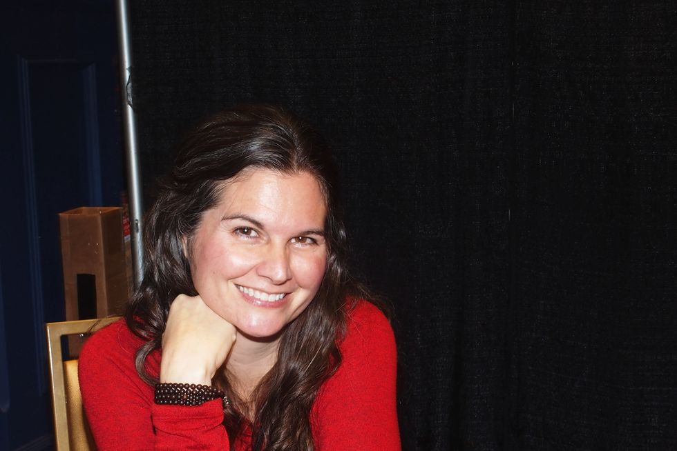 Lisa Jakub auf einem Kongress 2021, trägt einen roten Pullover und lächelt in die Kamera