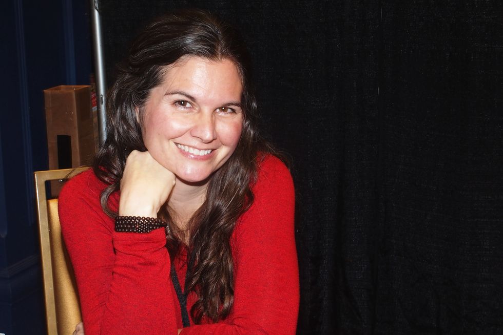 Lisa Jakub auf einem Kongress 2021, trägt einen roten Pullover und lächelt in die Kamera