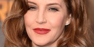 lisa marie presley slightly smiles at the camera, she wears bright red lipstick and her auburn hair is down