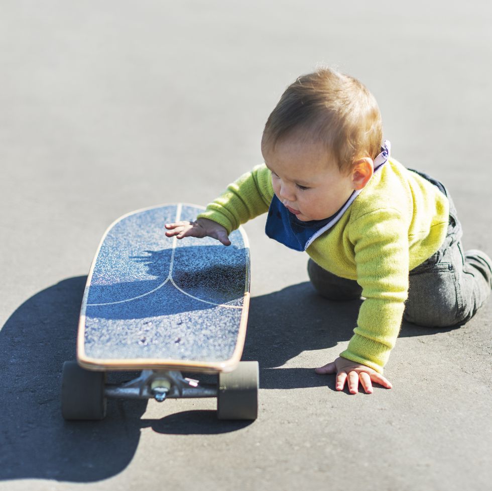 little baby boy playing with big skateboard in park