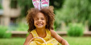 little black girl with bunny ears gathering easter eggs