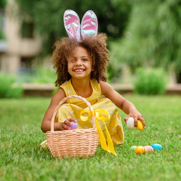 little black girl with bunny ears gathering easter eggs