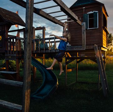 little boy hanging from monkey bars during vivid sunset