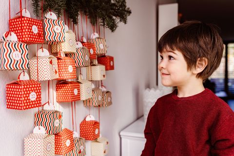 little child waiting to start opening handmade advent calendar hanging on wall