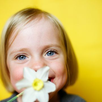 niña rubia de ojos claros oliendo flor