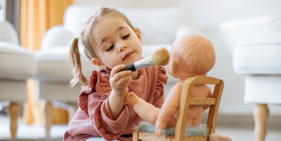 niña pequeña maquillando a su muñeco